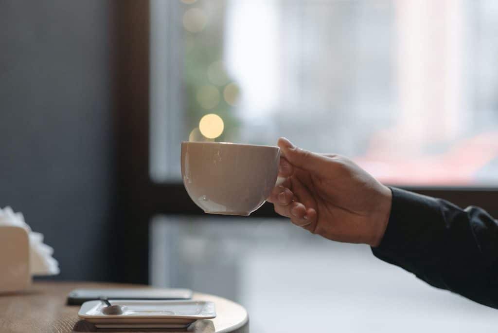 Person holding coffee cup for coffee decanter