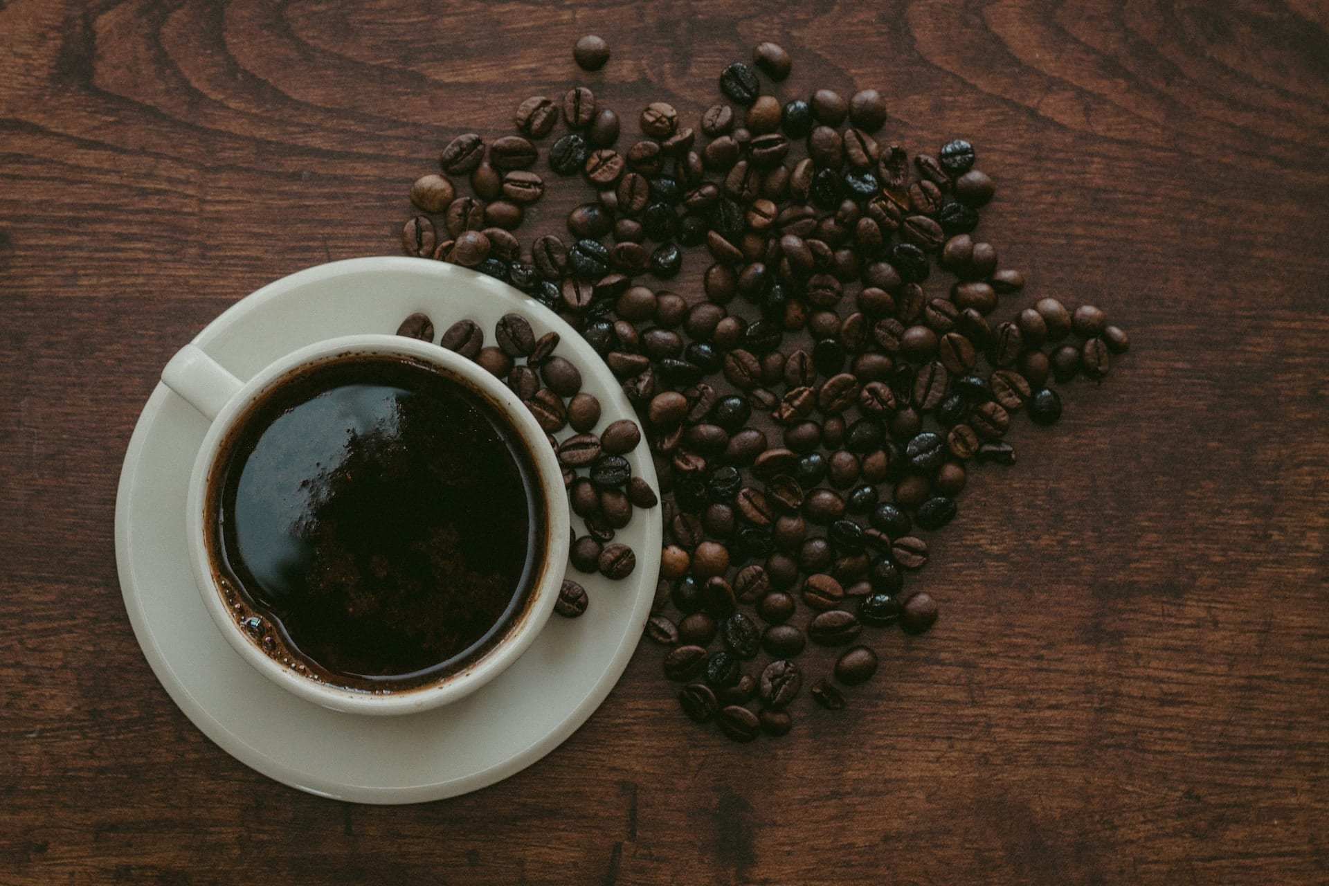 coffee beans surrounding a cup of black coffee
